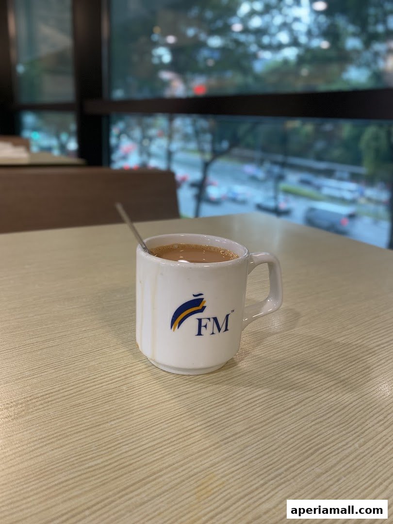 A white mug with the FM logo filled with a beverage sits on a table.