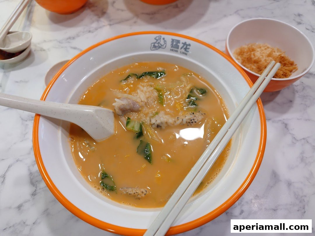 A bowl of savory soup with rice, meat, and vegetables, served with chopsticks and a side of shredded meat.