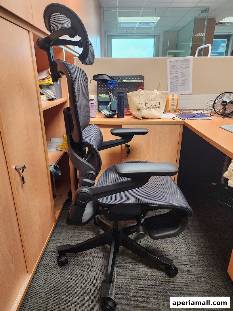 An ergonomic office chair with a footrest is shown in a modern office setting.