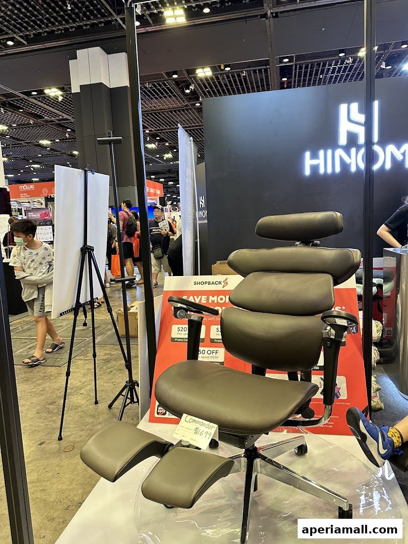A dark brown ergonomic chair with a footrest is displayed at the Hinomi Singapore Showroom.
