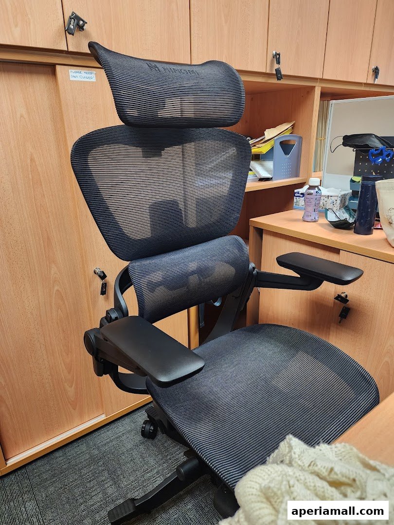 A black ergonomic chair with adjustable headrest and armrests in a showroom.