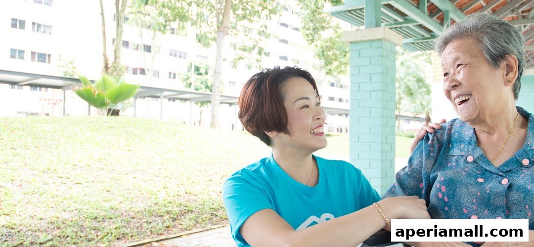 A caregiver smiles warmly while assisting an elderly woman outdoors.