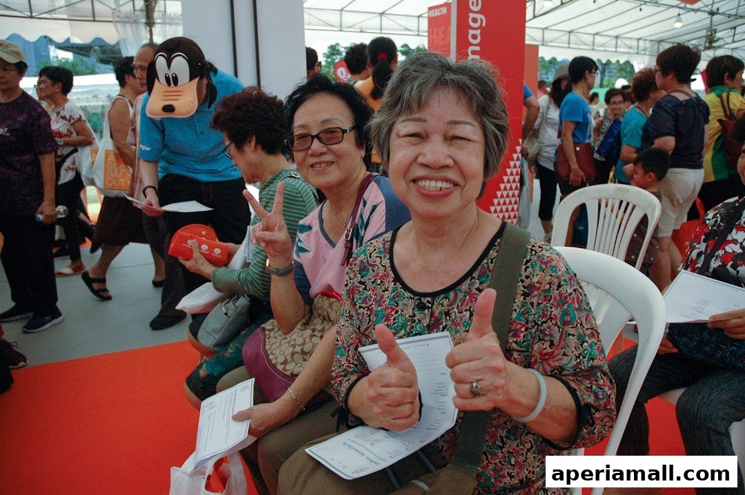 Smiling women giving thumbs up and peace signs at an event, with a Goofy mascot in the background.