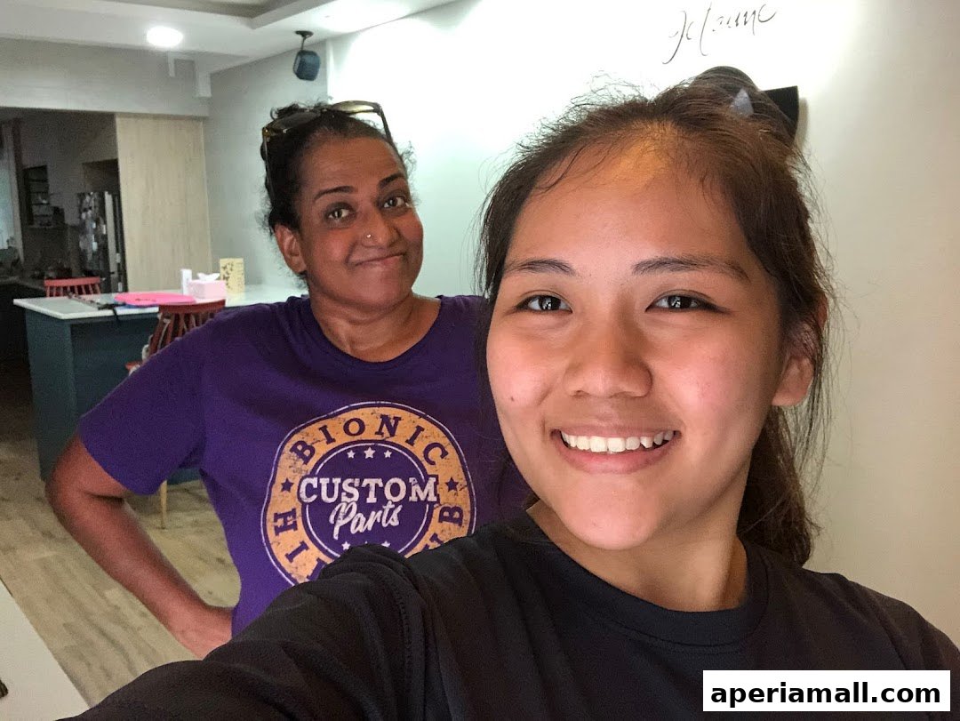 Two smiling women pose for a selfie in what appears to be a home or office setting.