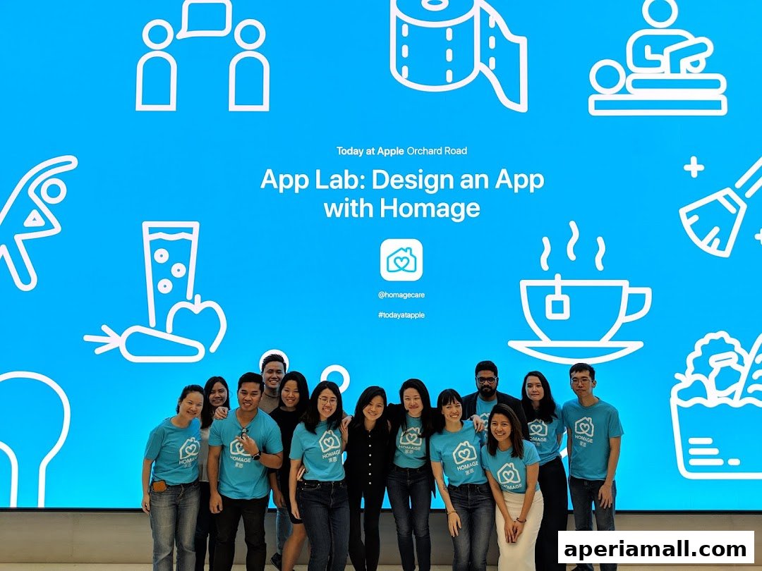 A group of people in blue t-shirts stand in front of a bright blue screen with icons and text.