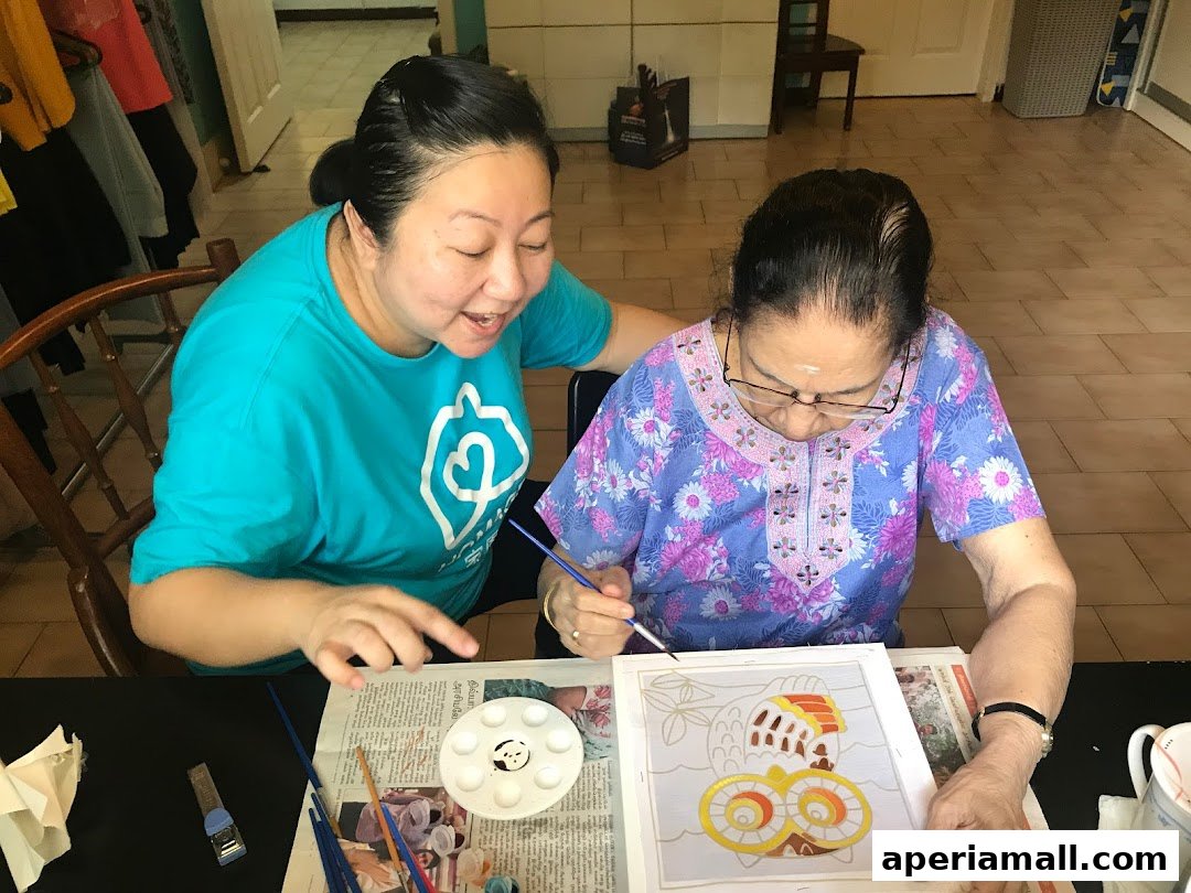 Two women are painting together, one assisting the other with a craft project.