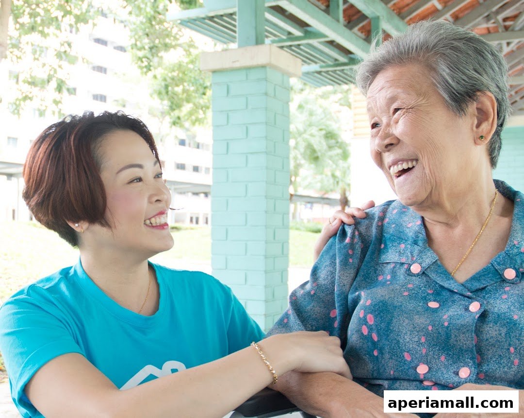 A caregiver smiles warmly while assisting an elderly woman outdoors.