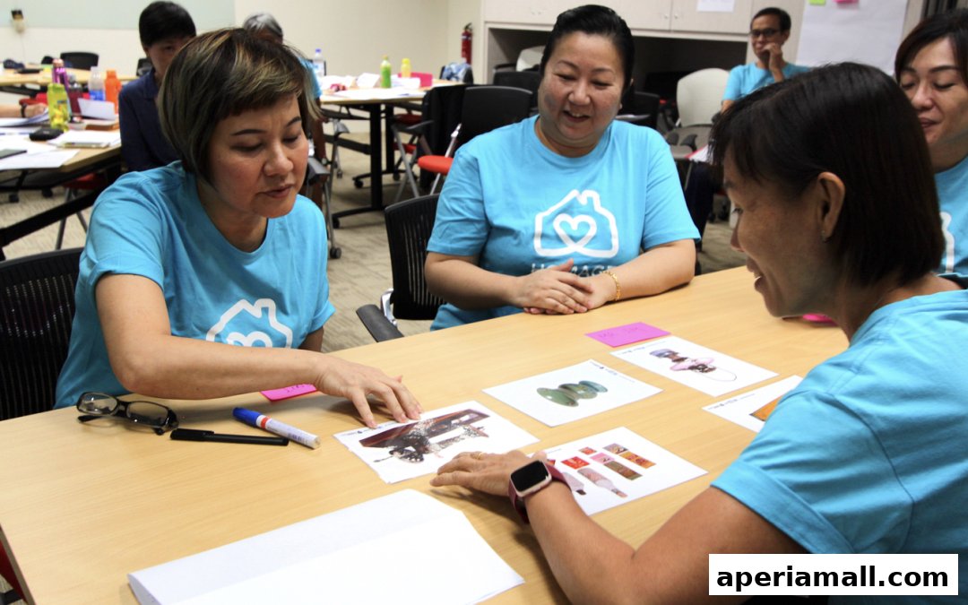 Team members in blue shirts with a house and heart logo collaborate around a table.