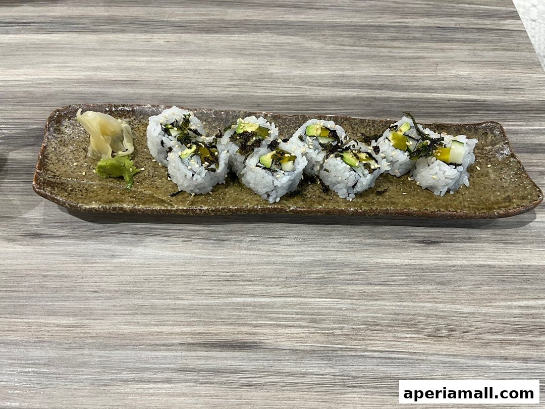 A plate of sushi rolls with avocado and seaweed, served with wasabi and ginger.