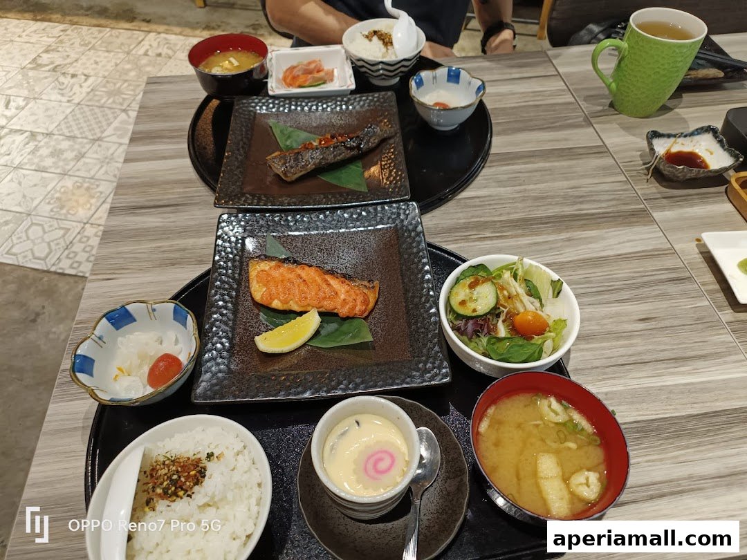 A table laden with delicious Japanese dishes, including grilled fish, rice, soup, and salad.