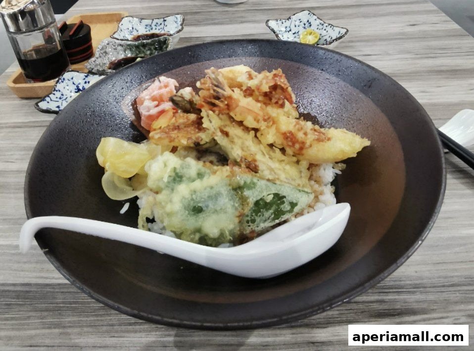 A close-up of a delicious tempura donburi with crispy shrimp and vegetables on rice.