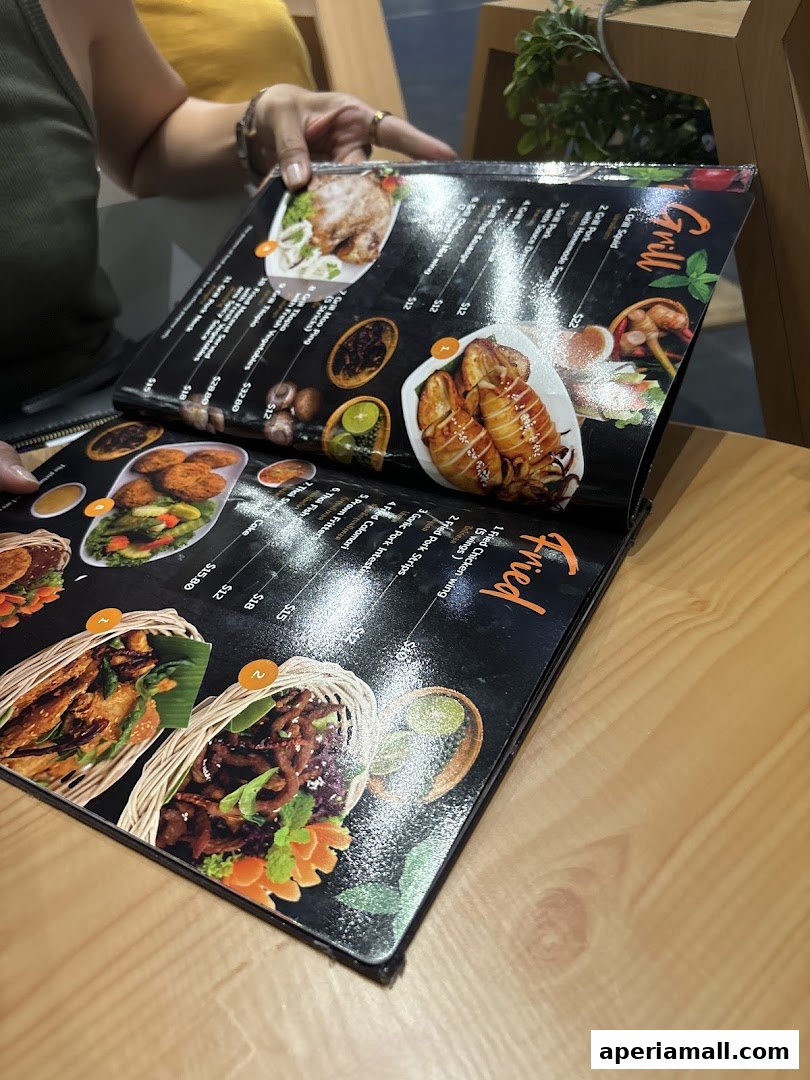 A person is looking at a menu from Im-Em Thai Kitchen with various Thai dishes.