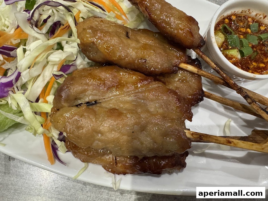 Close-up of grilled meat skewers served with a fresh cabbage and carrot salad and dipping sauce.