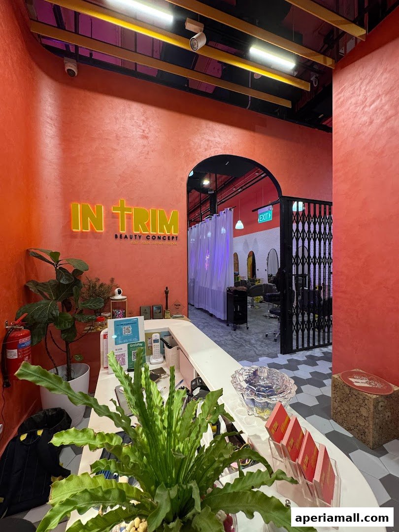 The reception area of a modern beauty salon with vibrant orange walls and a prominent logo.