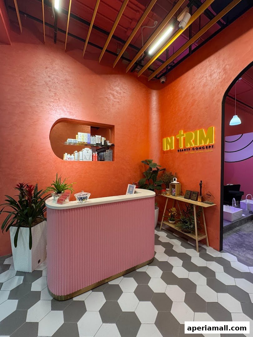 Interior of a beauty salon with a pink reception desk and orange walls.