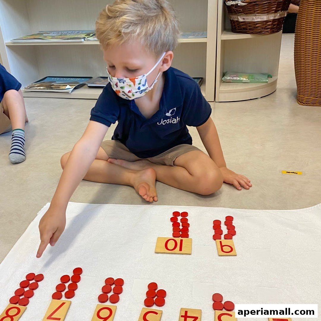 A young boy wearing a mask learns math with red counters and number cards.