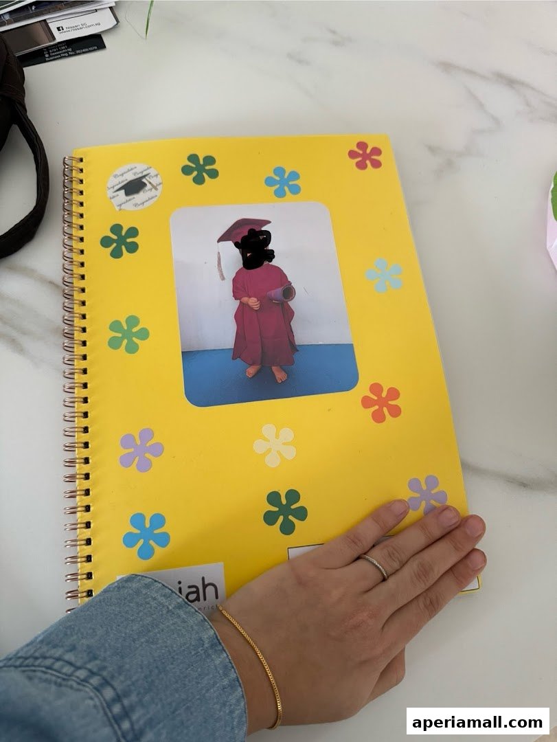 A yellow notebook with a child in graduation attire and colorful flower stickers.
