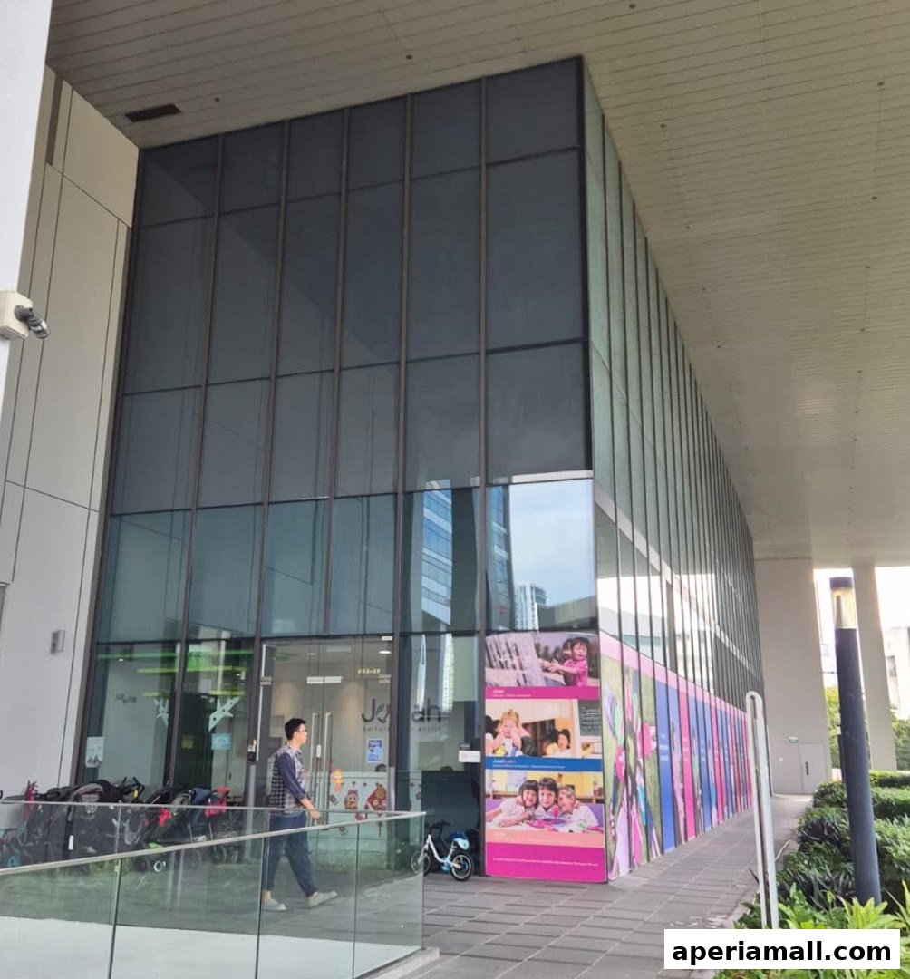 The exterior of Josiah Montessori Aperia, featuring a modern glass facade and colorful promotional posters.