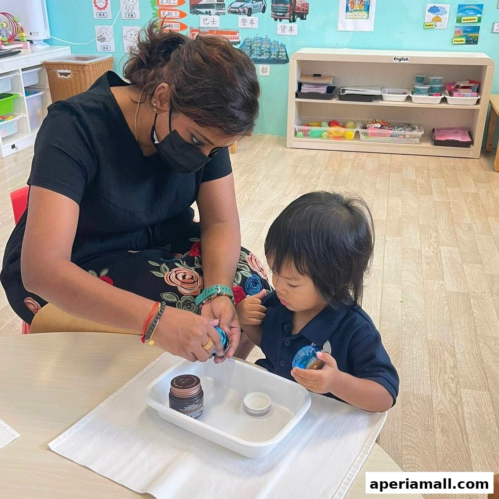 A teacher assists a young child with a hands-on activity at a table in a classroom.