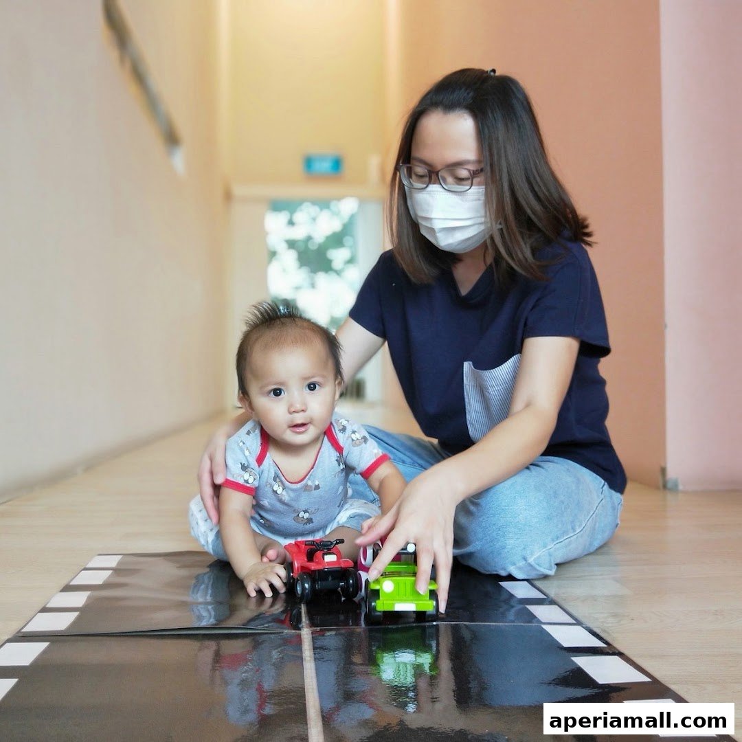 A woman in a mask plays with a baby and toy cars on a road mat.