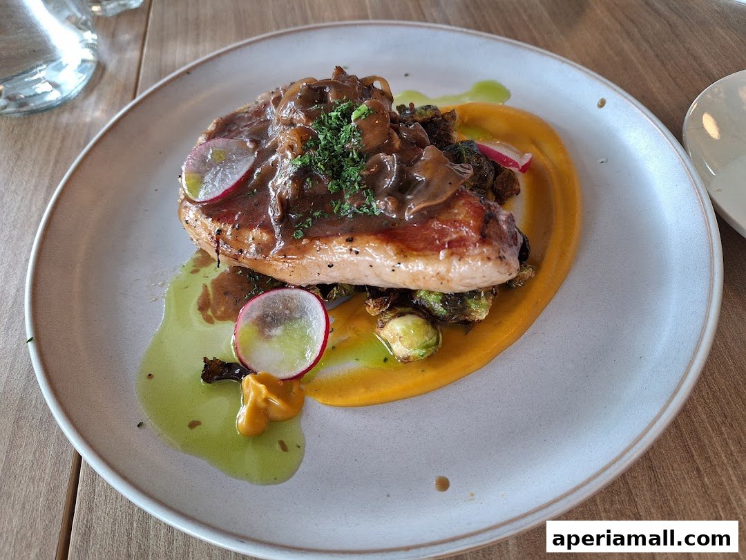 A beautifully plated dish featuring chicken breast with mushroom sauce, Brussels sprouts, and a vibrant puree.