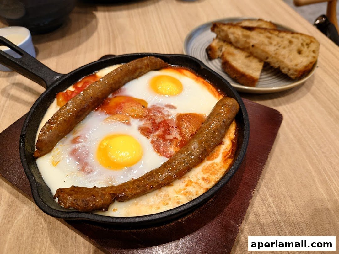 A hearty breakfast dish with sausages and eggs served in a cast iron pan with toast.