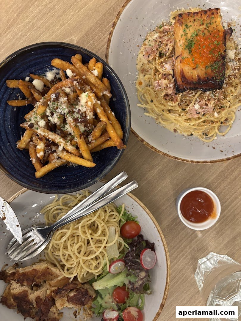 A top-down view of three dishes: truffle fries, salmon pasta, and chicken pasta with salad.
