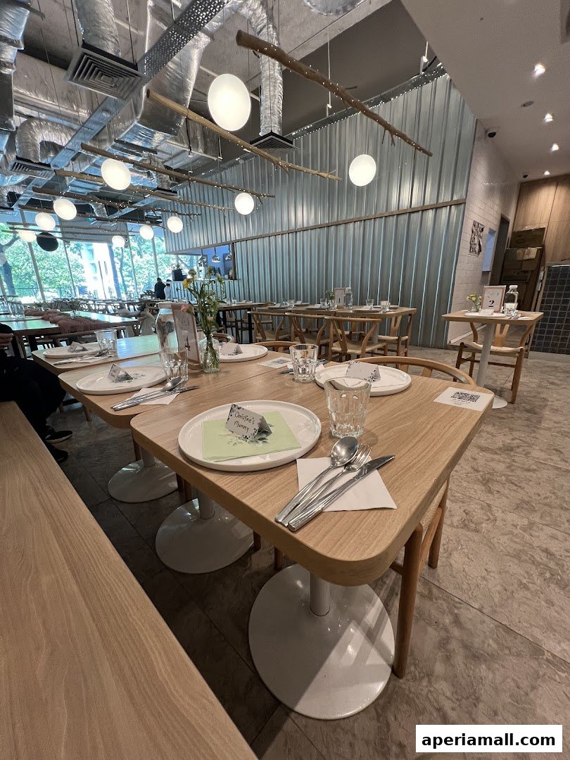 Interior view of a modern restaurant with wooden tables and chairs, set for dining.