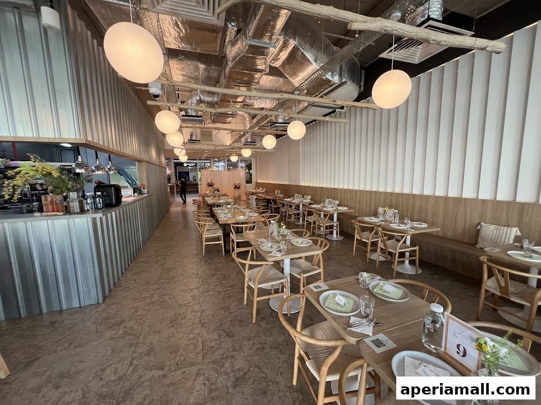 Interior of a modern restaurant with wooden tables, chairs, and ambient lighting.