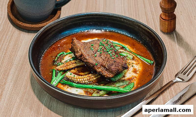 A close-up of a gourmet dish featuring a slice of steak with vegetables and sauce.