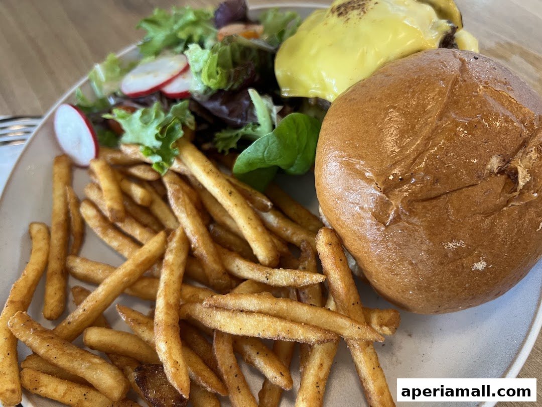 A delicious burger with fries and a side salad on a plate.
