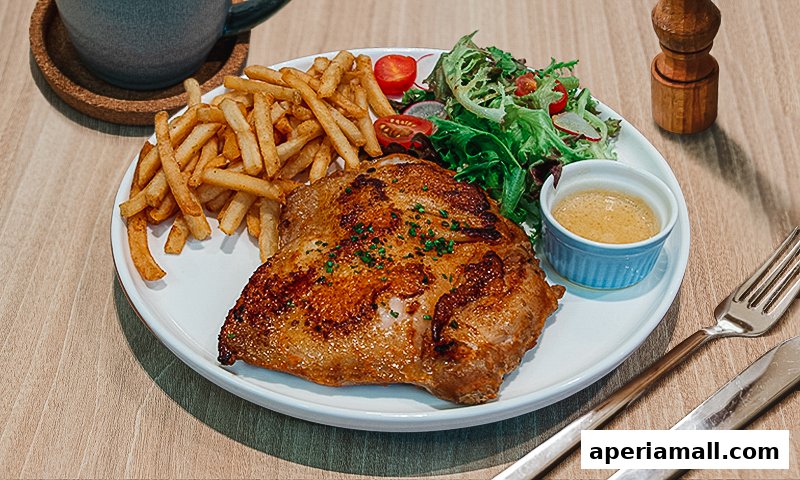 A plate of grilled chicken with fries, salad, and a dipping sauce.