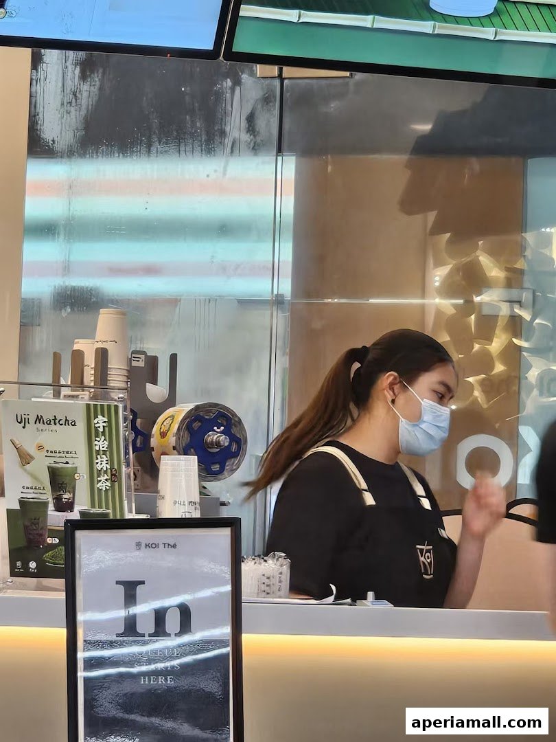 A staff member at KOI Thé Aperia Mall prepares drinks behind the counter.