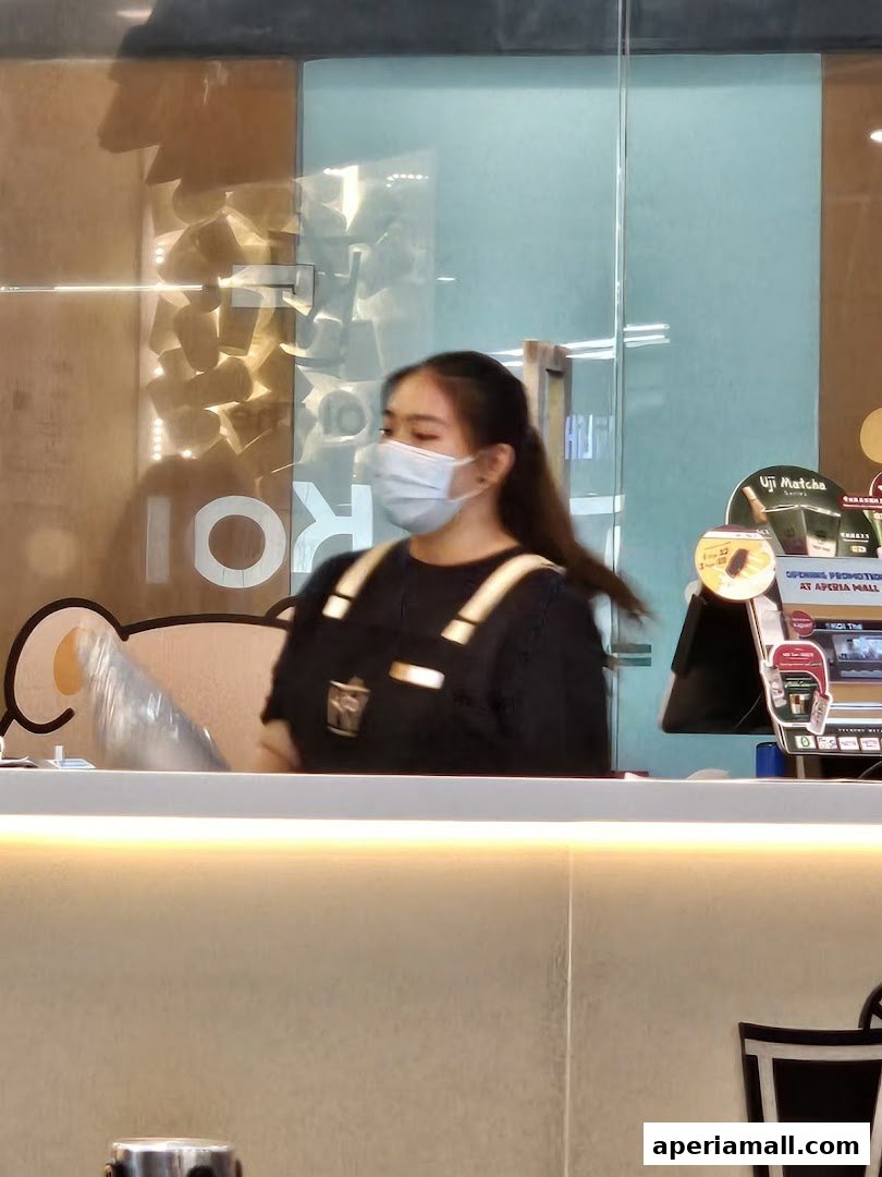A staff member wearing a mask stands behind the counter at KOI Thé.