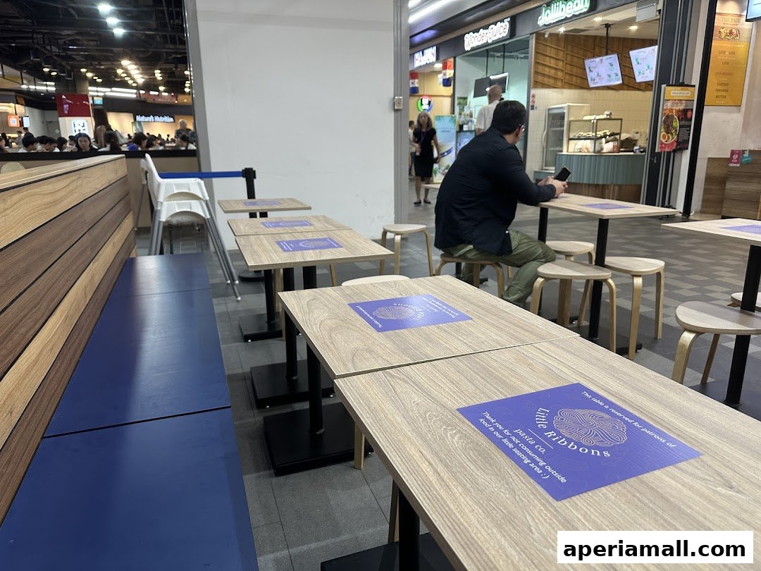 Seating area with tables and chairs at Little Ribbons Pasta Co. with other shops in the background.