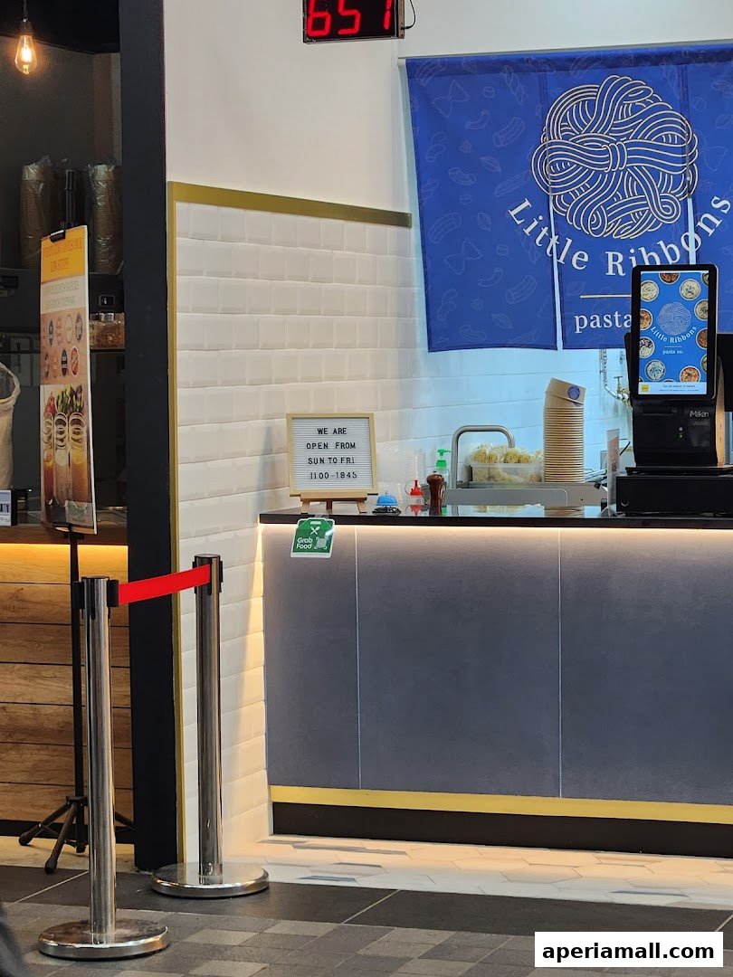 The counter area of Little Ribbons Pasta Co. with a sign indicating operating hours.