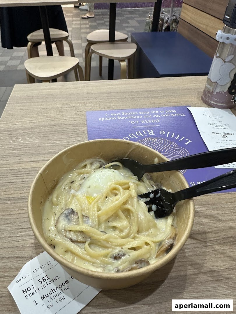 A bowl of creamy mushroom linguine pasta with a poached egg, served with cutlery.