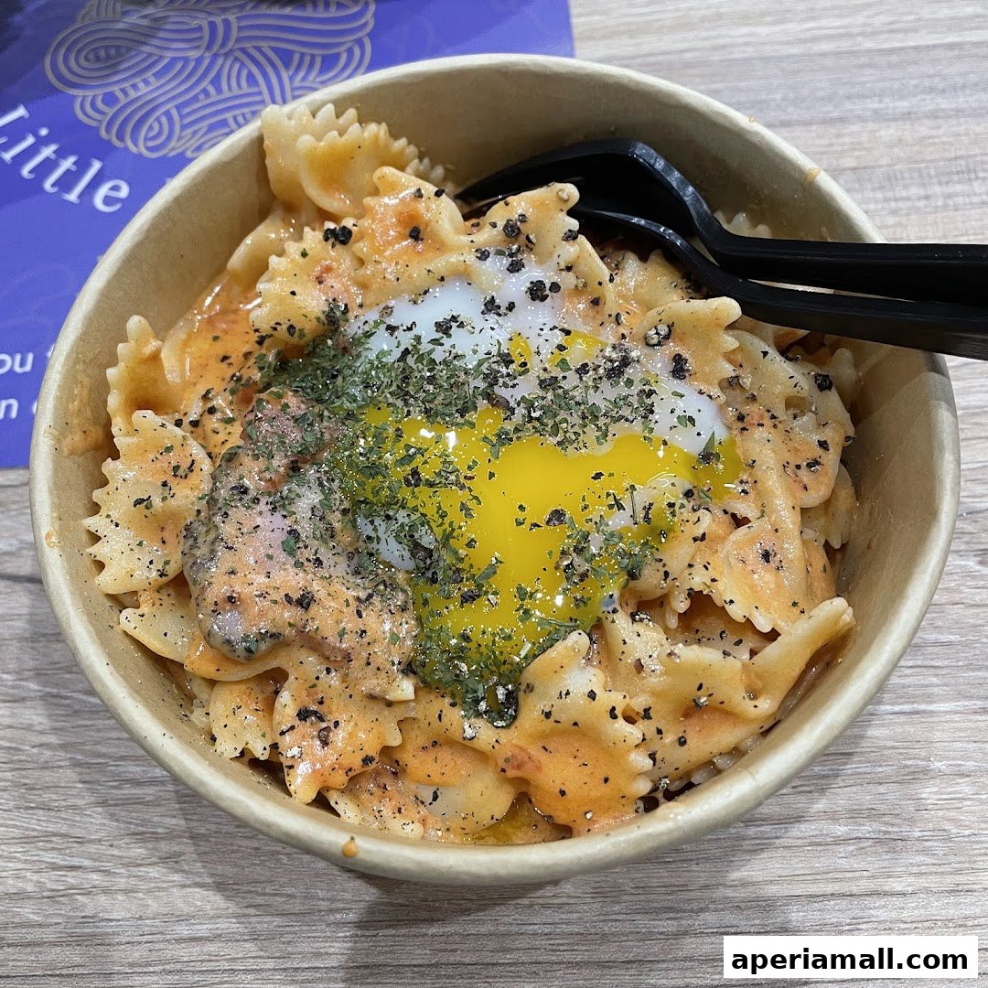 A bowl of farfalle pasta with a creamy sauce, topped with a runny egg yolk and herbs.