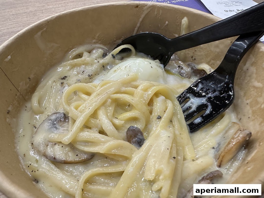 A close-up of a creamy pasta dish with mushrooms and a poached egg, served in a to-go container.