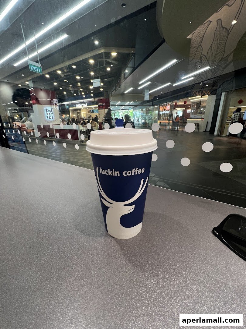 A Luckin Coffee cup sits on a counter with a mall interior visible in the background.