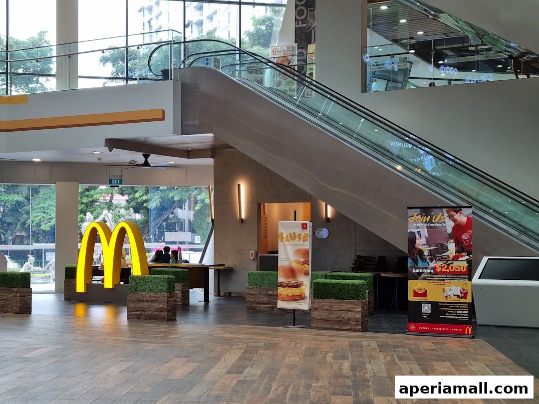 McDonald's golden arches visible inside a mall with an escalator and promotional posters.