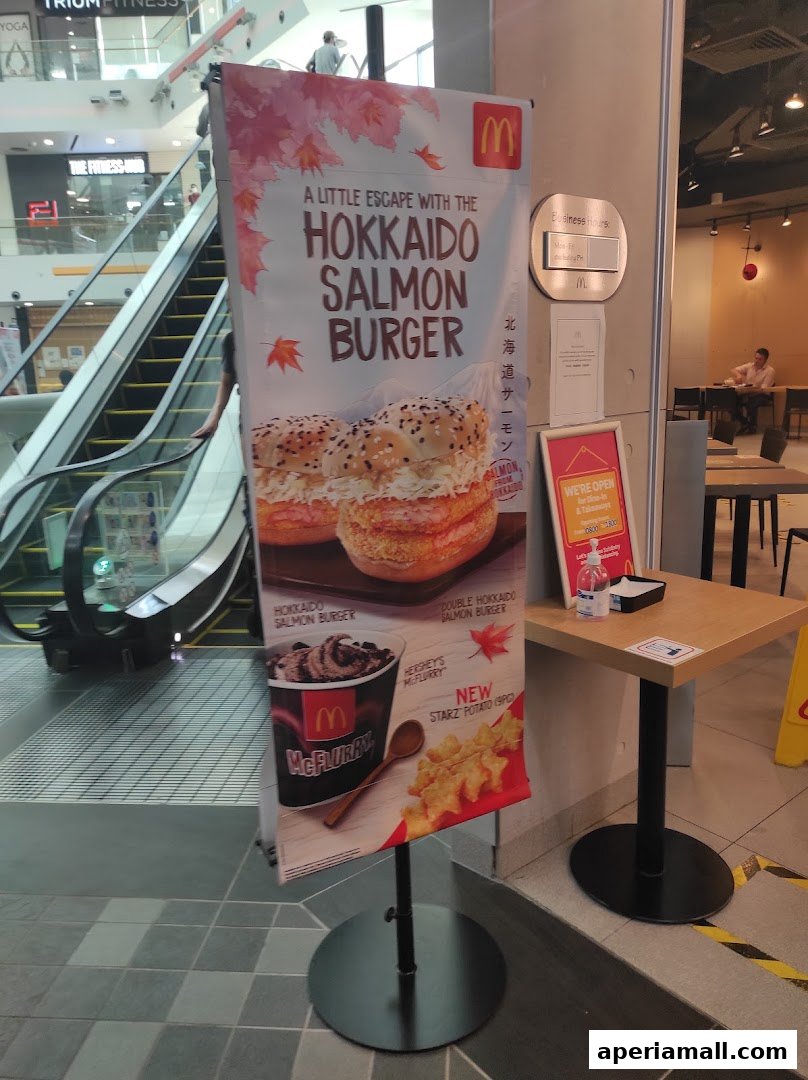 A promotional stand for McDonald's Hokkaido Salmon Burger and McFlurry is displayed near an escalator.