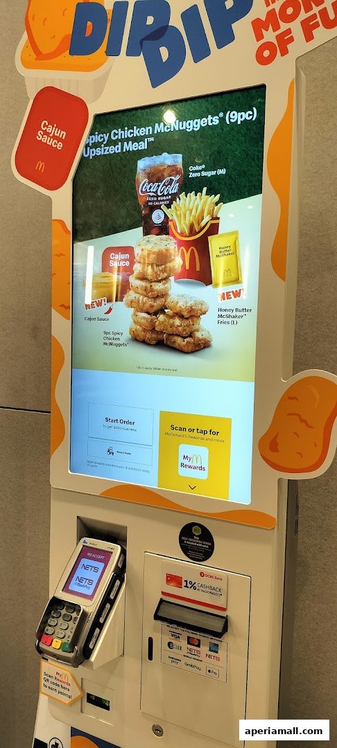 A McDonald's self-order kiosk displaying a Spicy Chicken McNuggets meal with Cajun sauce and Honey Butter McShaker Fries.