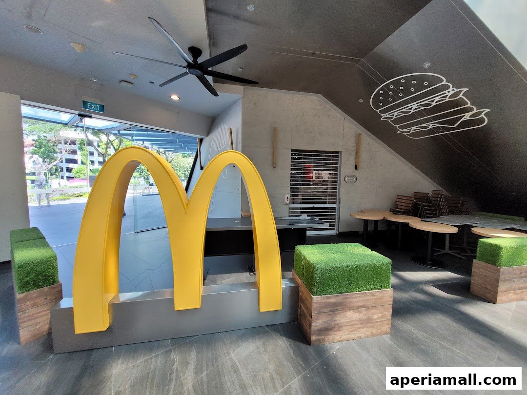 The iconic golden arches of McDonald's are prominently displayed with seating and a burger graphic on the wall.