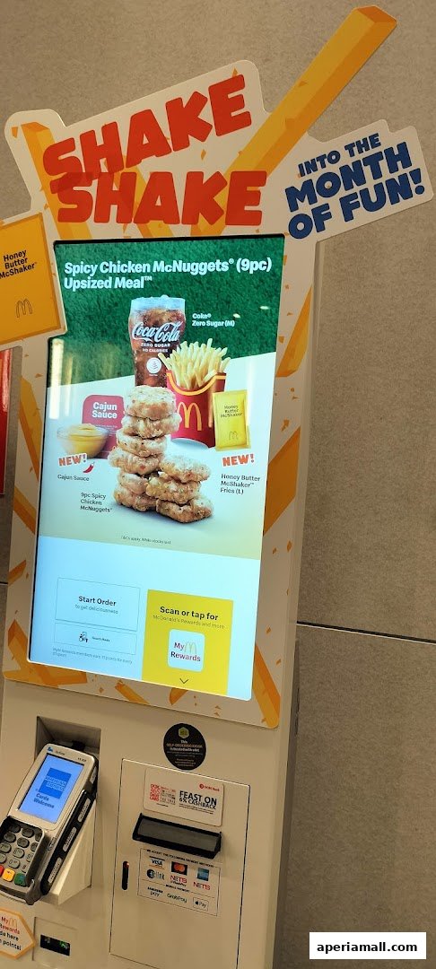 A McDonald's self-order kiosk displaying a Spicy Chicken McNuggets Upsized Meal promotion.