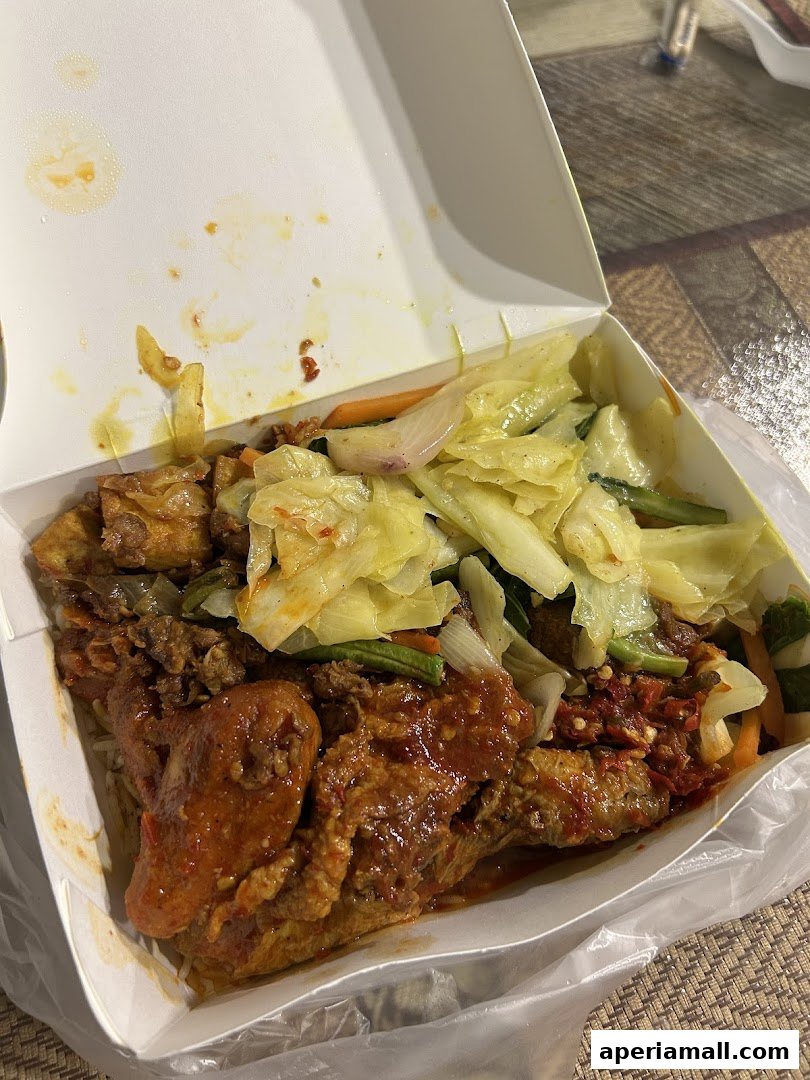 A takeaway box filled with rice, fried chicken, and stir-fried vegetables.