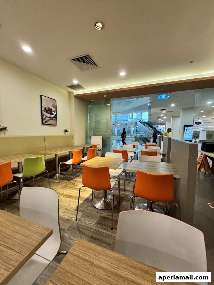 Interior view of a modern cafe with colorful chairs and wooden tables.