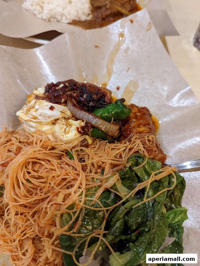A close-up of a delicious meal featuring noodles, fried egg, vegetables, and meat.
