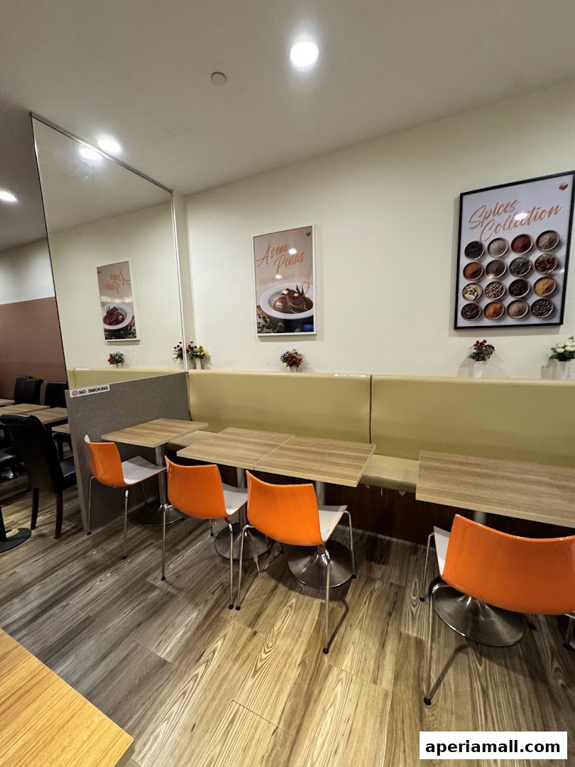 Interior of a restaurant with tables, orange chairs, and spice collection posters on the wall.