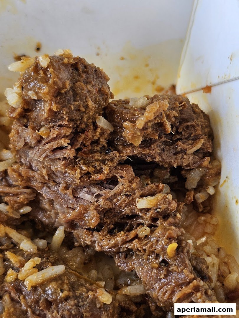 Close-up of tender, shredded meat with rice, seasoned with spices.